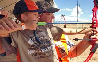 Become a Wildlife Conservation Volunteer. (Photo of archery instructor helping youth). New Mexico Department of Game and Fish