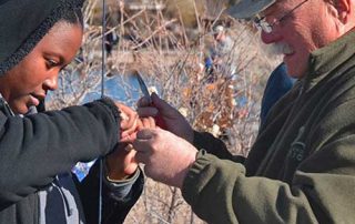 Become a Wildlife Conservation Volunteer. (Photo of fishing instructor helping youth). New Mexico Department of Game and Fish