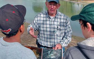 Become a Wildlife Conservation Volunteer. (Photo of fishing instructor helping youth). New Mexico Department of Game and Fish