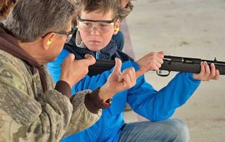 Become a Wildlife Conservation Volunteer. (Photo of hunting instructor helping youth). New Mexico Department of Game and Fish