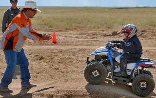 Become a Wildlife Conservation Volunteer. (Photo of off-highway vehicle instructor helping youth). New Mexico Department of Game and Fish